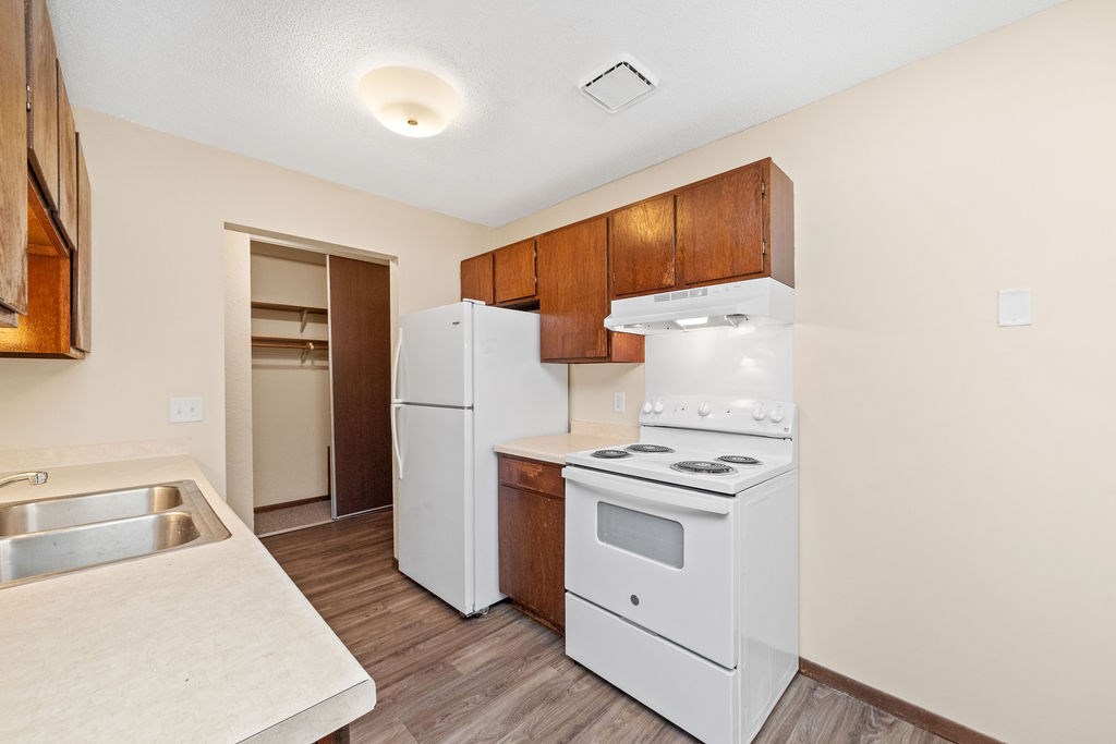 A kitchen with white appliances and wooden cabinets.