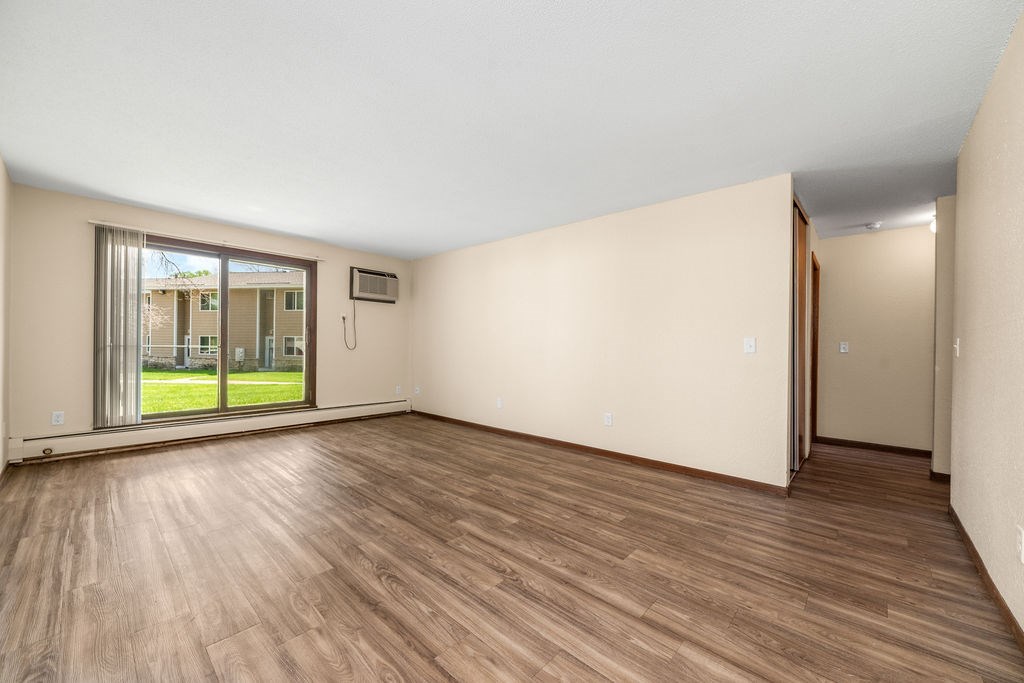 A room with wooden flooring and a sliding glass door leading to a balcony.