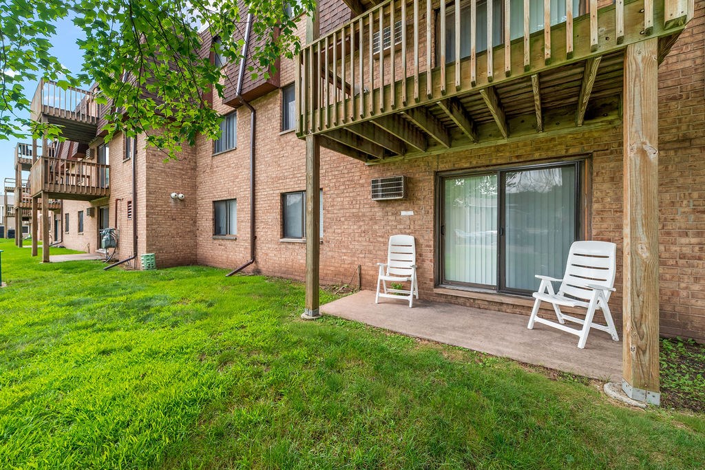 A balcony with two chairs and a table is on the right side of a brick building.