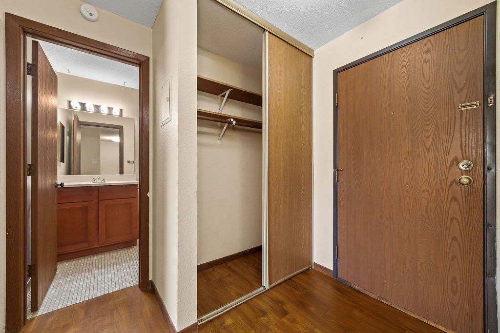 A wooden door is open to a bathroom with a mirror.