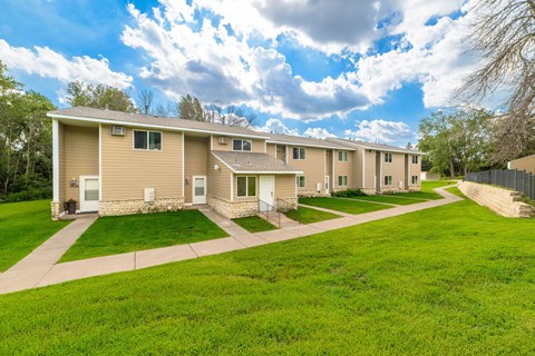 A row of houses with green lawns in front.