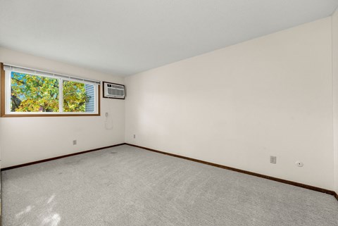 A room with a window and a carpeted floor.