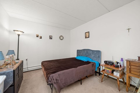 A bedroom with a bed, nightstand, and a lamp.