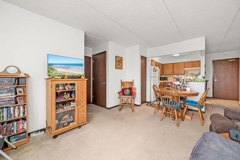 A living room with a television, a bookshelf, and a dining area.