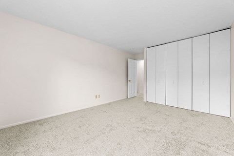 A room with white walls and carpeted floor with a white wardrobe.