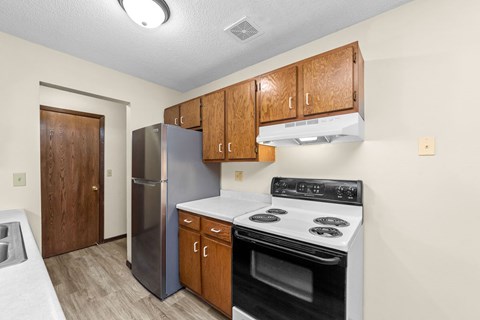 A kitchen with a stove, refrigerator, and cabinets.