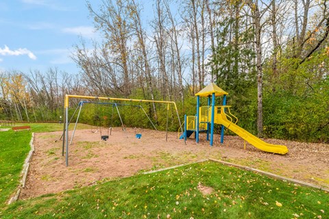 A playground with a yellow slide and a blue and yellow tower.