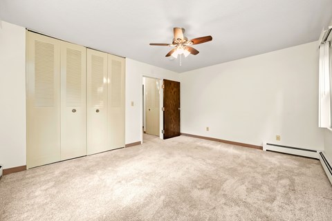 A room with a ceiling fan and carpeted floor.