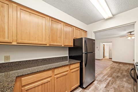 A kitchen with wooden cabinets and a black refrigerator.