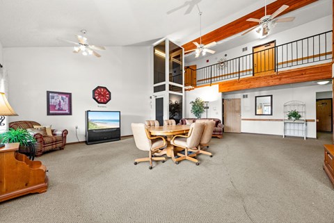 A living room with a television, a couch, a chair, a table, and a plant.