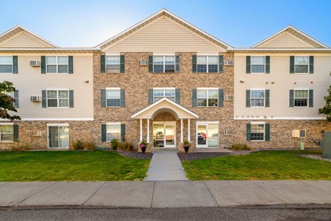 A large apartment building with a front entrance and a walkway leading to it.