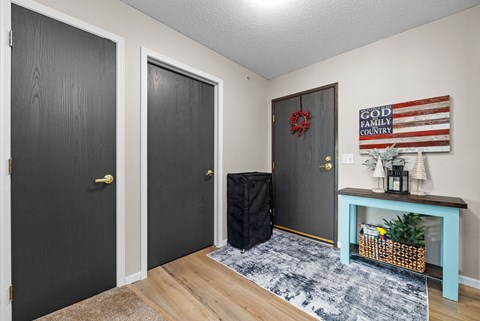 A room with a black door, a grey door, and a black suitcase on the floor.