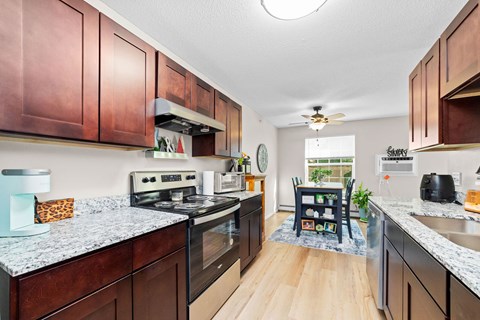 A kitchen with dark wood cabinets and a granite counter top.