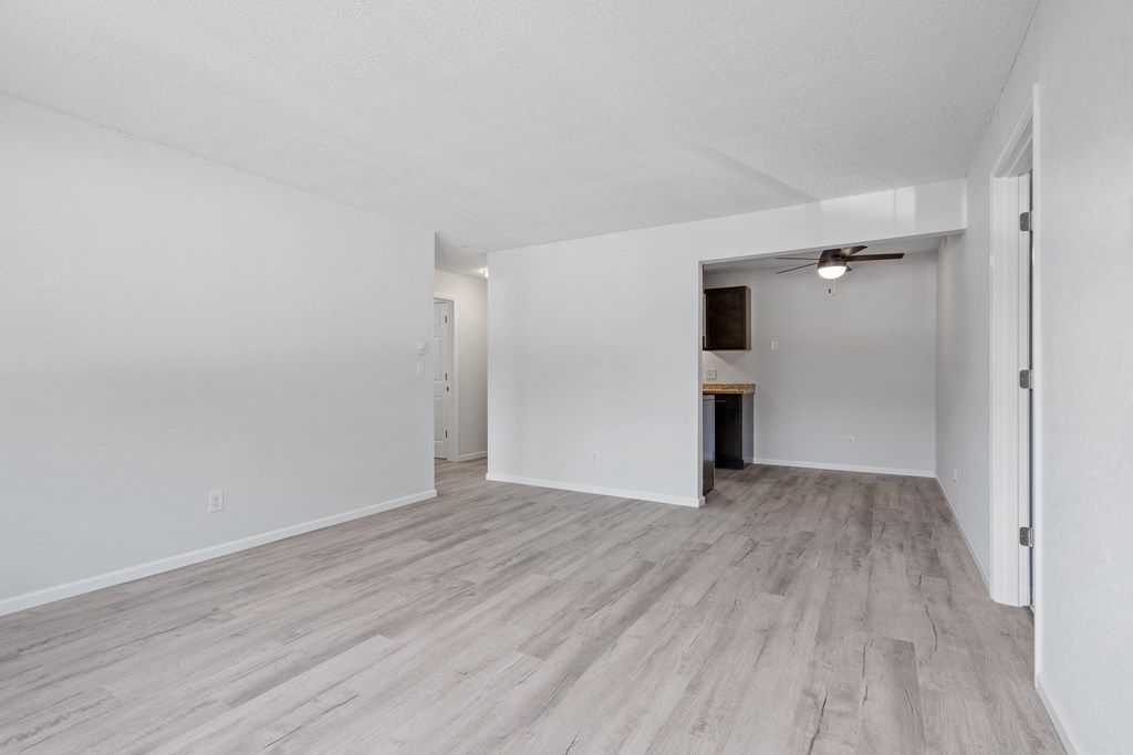 an empty living room with white walls and wood flooring