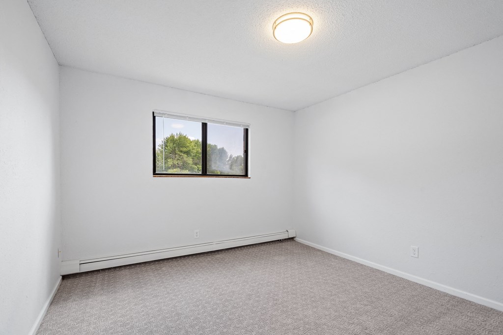 an empty room with white walls and a window