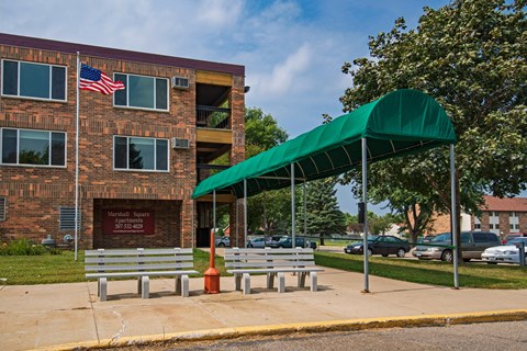 a building with two benches and a green canopy in front of it