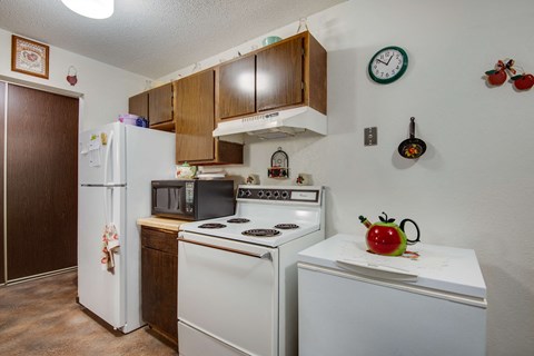 a kitchen with white appliances and wooden cabinets and a refrigerator