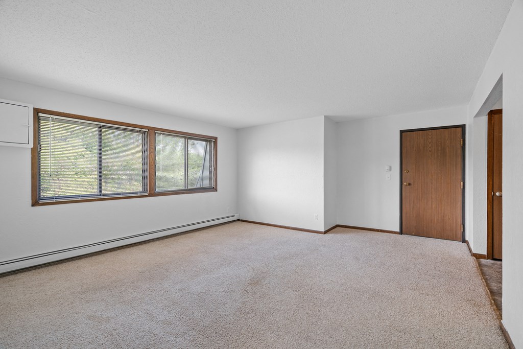 an empty living room with a large window and a door