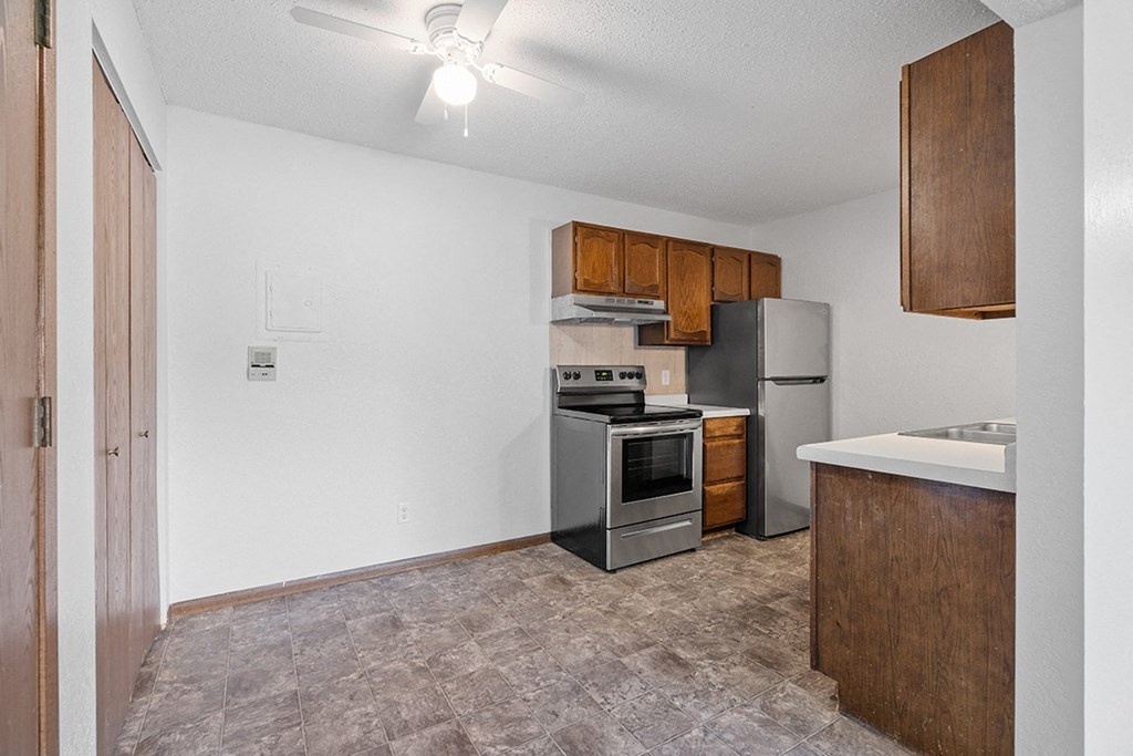 an empty kitchen with stainless steel appliances and wooden cabinets