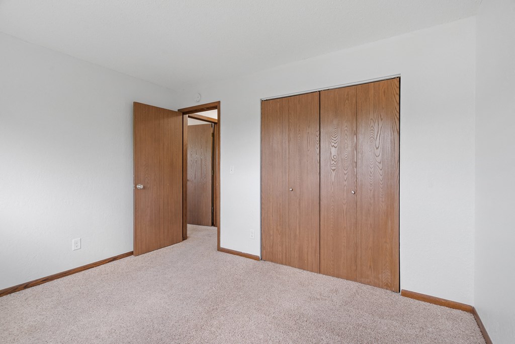 a bedroom with two closet doors and a carpeted floor