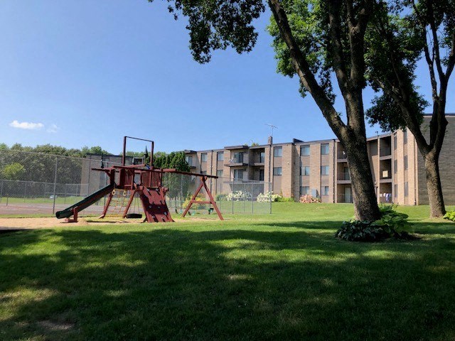 an empty swing set in a park next to an apartment building