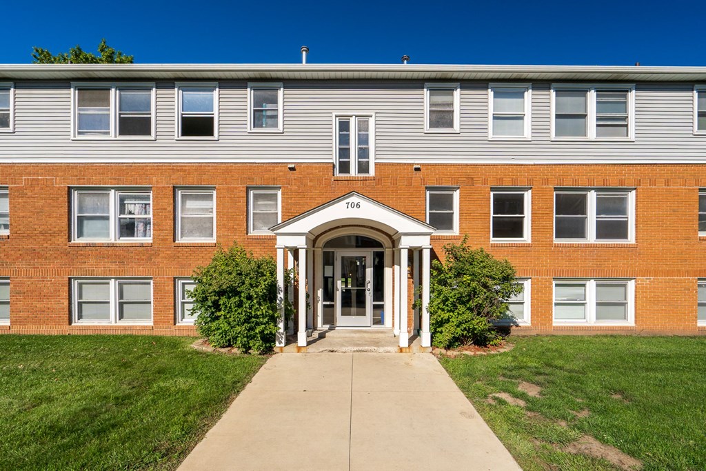 the front of a brick building with a sidewalk in front