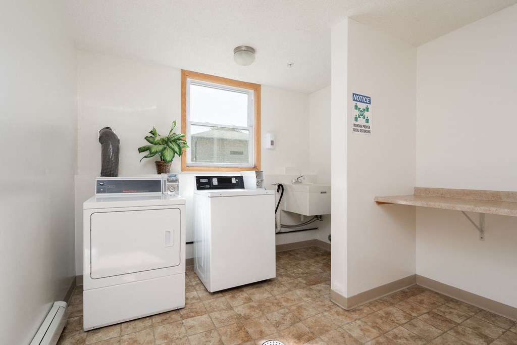 a washer and dryer in a laundry room with a sink and a window