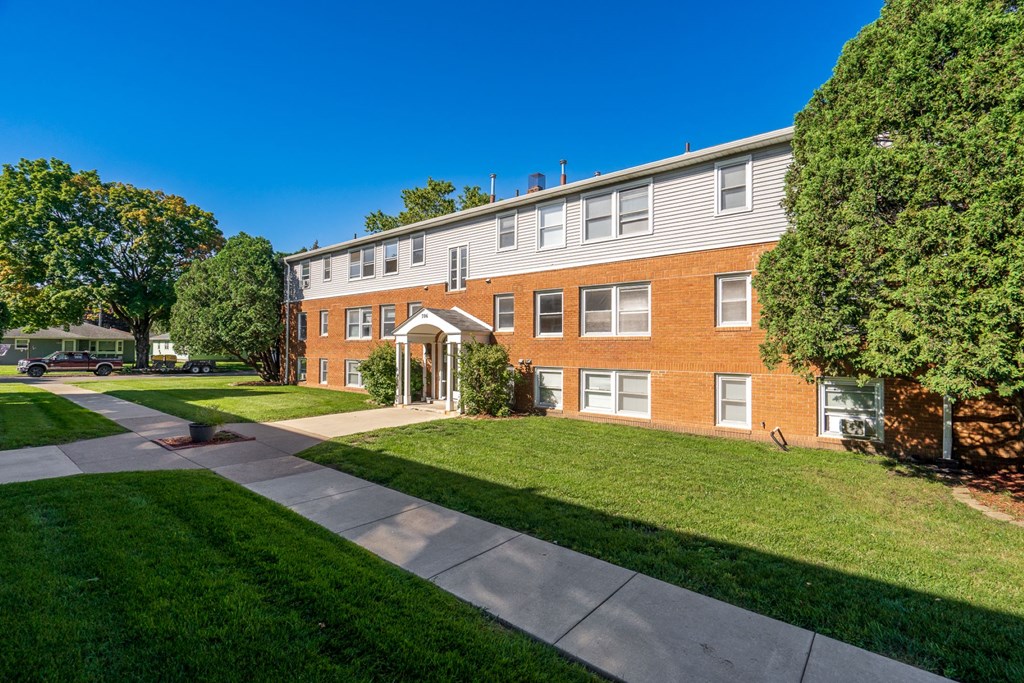 exterior view of a brick building with green grass and trees