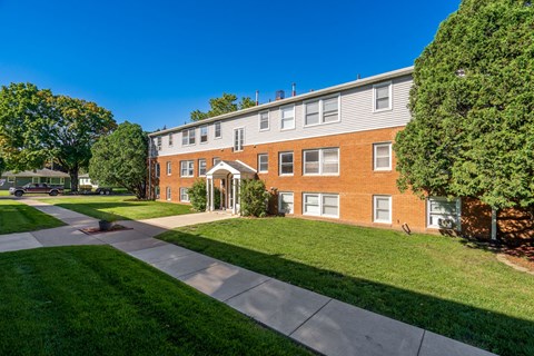 exterior view of a brick building with green grass and trees