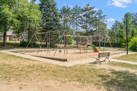 a playground with a swing set and a bench in a park
