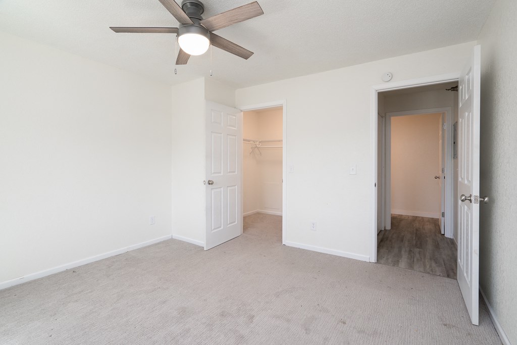 an empty bedroom with a ceiling fan and a closet