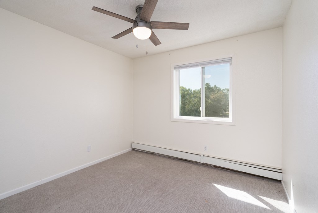 an empty room with a ceiling fan and a window