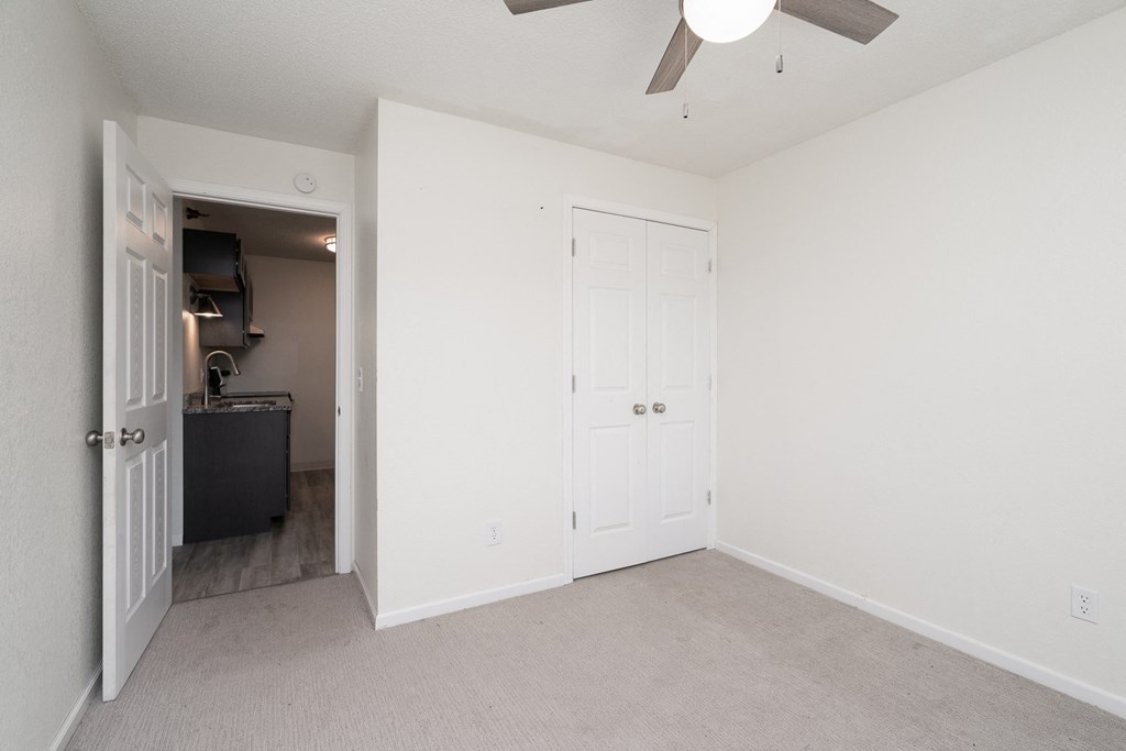 an empty bedroom with white walls and a ceiling fan