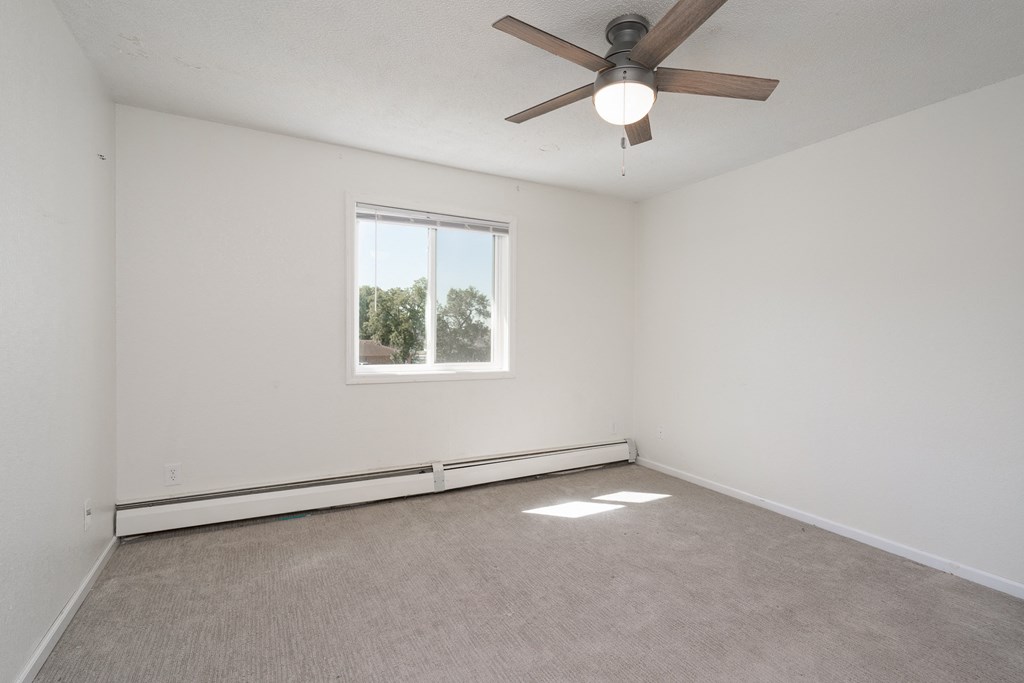 an empty living room with a ceiling fan and a window