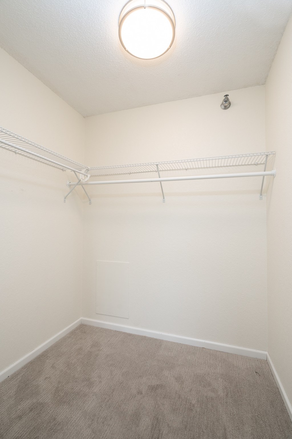 an empty room with a white wall and a ceiling light