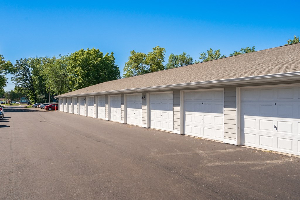 a row of garages with white garage doors in a parking lot
