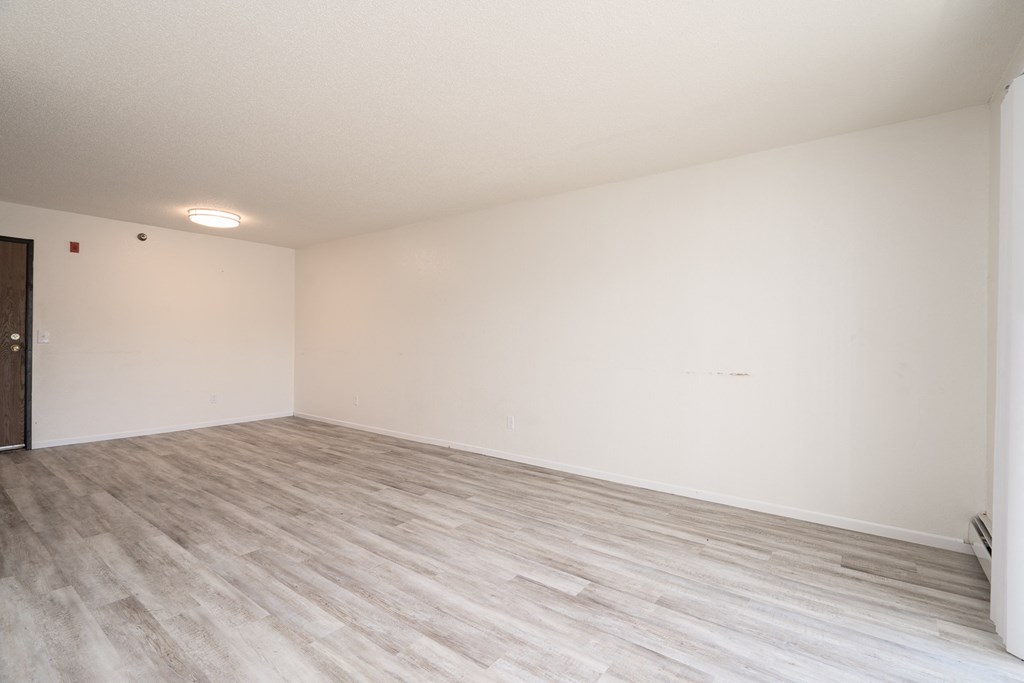an empty living room with wood flooring and white walls