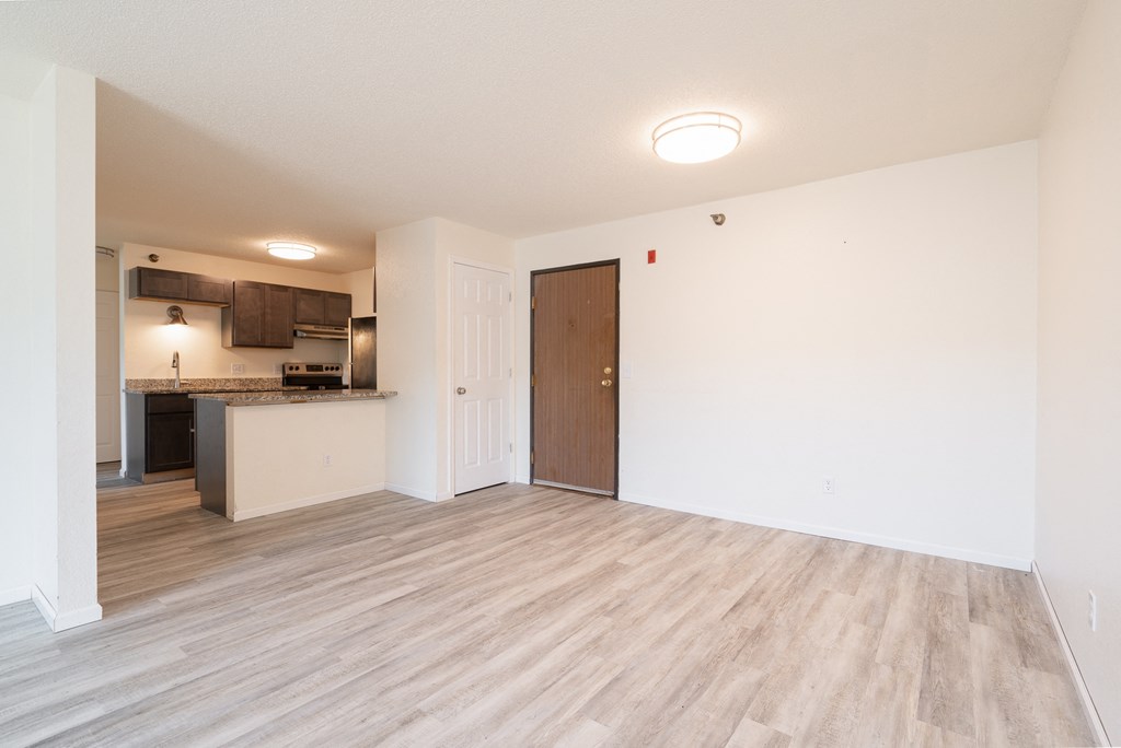 the living room and kitchen of an apartment with wood flooring