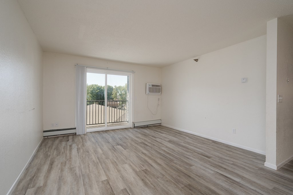an empty living room with a door to a balcony
