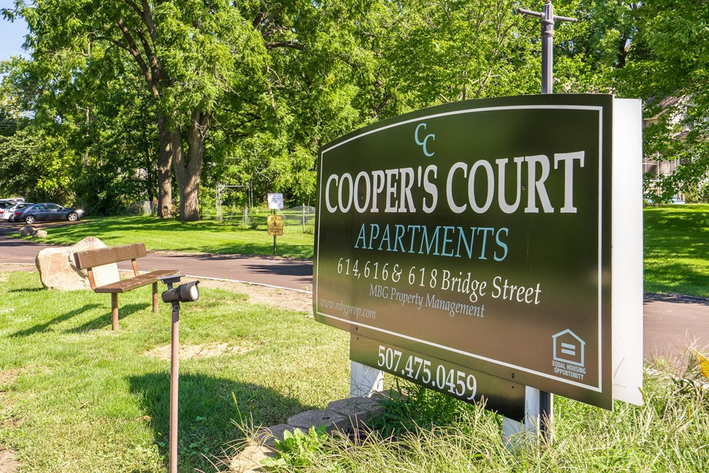 a sign for coopers court apartments in a park