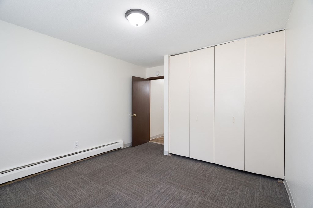 a bedroom with white cabinets and a door to a closet