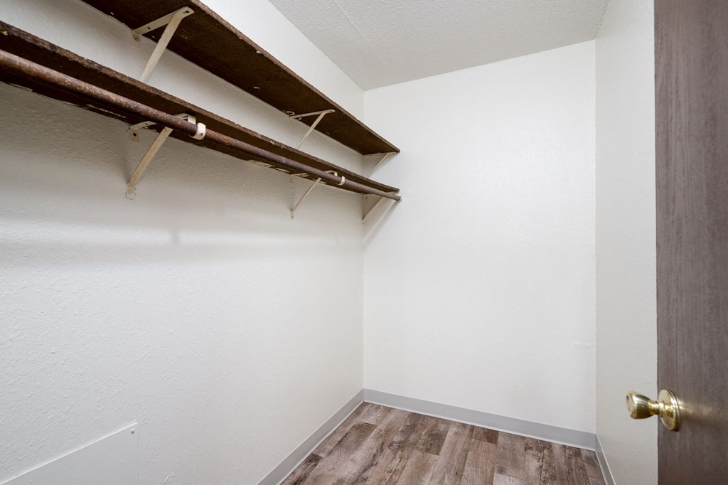 an empty closet in a room with wood flooring and white walls