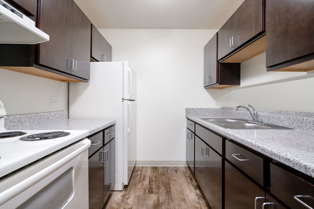 an empty kitchen with white appliances and granite counter tops