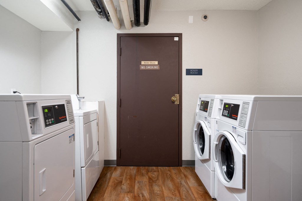 a laundry room with two washers and two dryers and a brown door