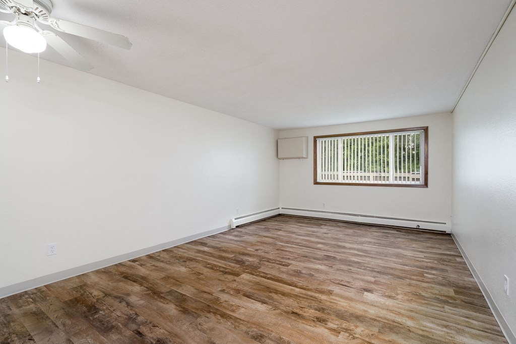 an empty living room with wood flooring and a window