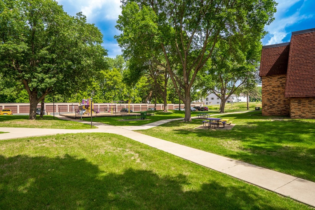 a park with trees and a sidewalk and a school building