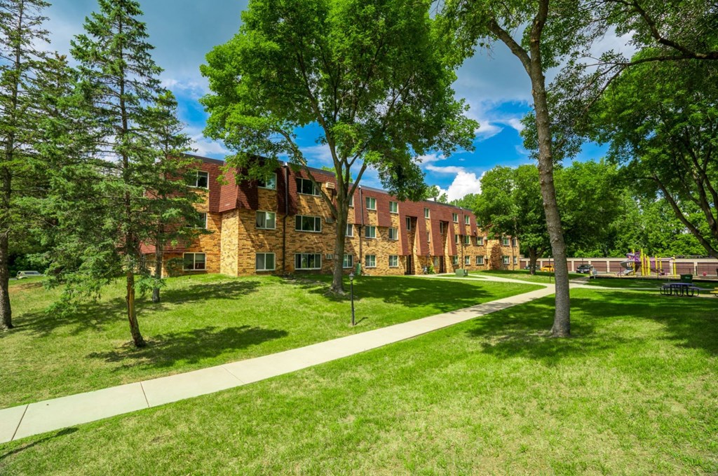 a brick building with grass and trees in front of it