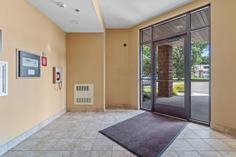 a lobby with a door and a rug in front of a glass door