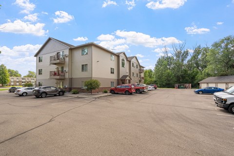 an empty parking lot with cars in front of apartment buildings
