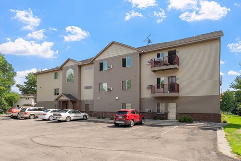 an apartment building with cars parked in a parking lot